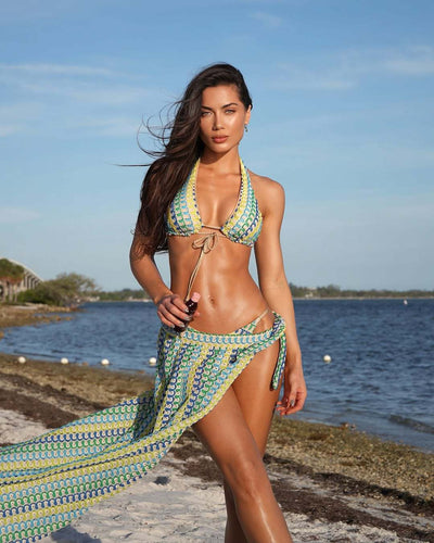 Woman in a blue, green, and yellow patterned halter bikini top and matching flowy sarong on a sunny beach. - Image 8