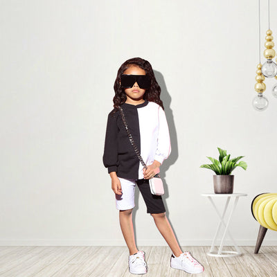 Woman wearing a black and white color-block long-sleeve top and matching shorts with white sneakers. - Image 22