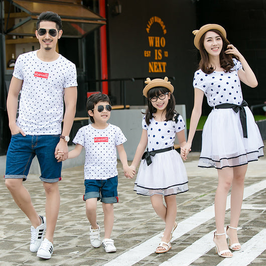 Family of four wearing matching white and black polka dot outfits. Dad and son in t-shirts, mom and daughter in dresses. - Image 9