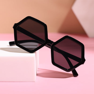 Red hexagonal children's sunglasses with dark lenses on a pink surface with a white block. - Image 2