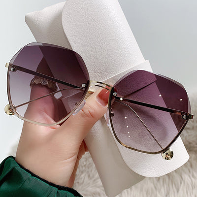 Elegant fashion sunglasses with gold metal frames and pink gradient lenses, held against a white case. - Image 14