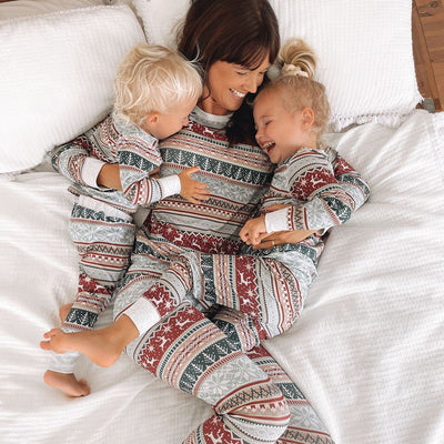 Family of four wearing matching Christmas pajamas with red, green, and grey Fair Isle reindeer and snowflake pattern. - Image 4