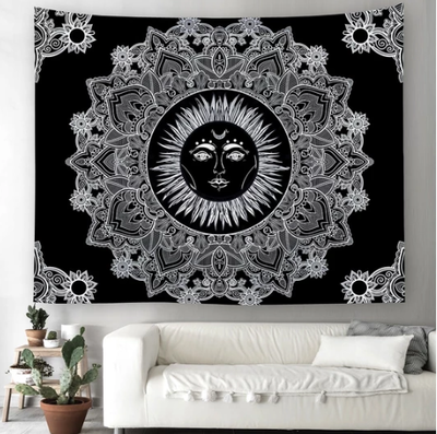 Black and white celestial sun tapestry with intricate mandala patterns hanging above a white sofa.