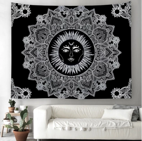 Black and white celestial sun tapestry with intricate mandala patterns hanging above a white sofa.
