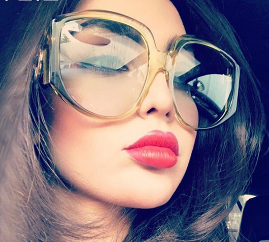 Oversize round sunglasses for women with olive frames, dark gradient lenses, and a gold emblem on the temples.