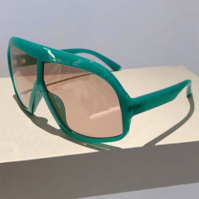 Oversized women's shield sunglasses with a tortoiseshell frame and brown-tinted lenses, held by a hand. - Image 21