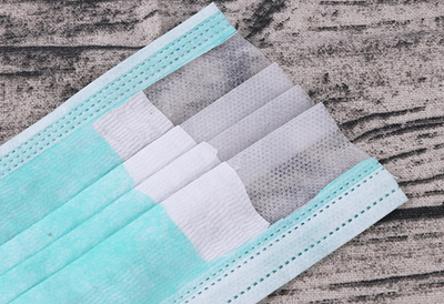 Stack of pink disposable non-woven face masks, with one unfolded and one folded, on a light wood surface. - Image 9