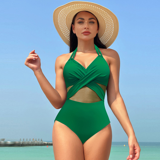 Woman in a green halter-neck one-piece swimsuit with cross-strap design and mesh cutouts, on a beach. - Image 21