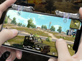 Black mobile gaming trigger with a silver button and nine circular control buttons, clamped onto a white smartphone. - Image 10