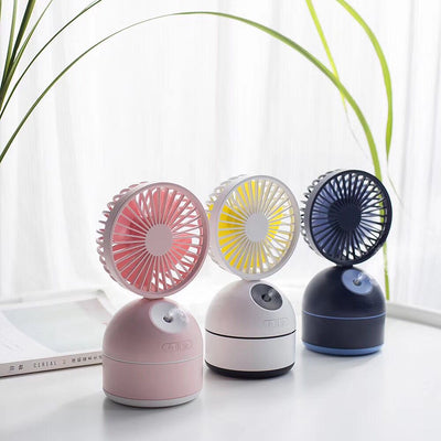 Dark grey fan humidifier with a round fan head and spherical base, emitting mist, on a white desk. - Image 3