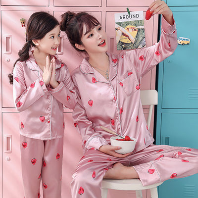 Mother and daughter in matching light blue satin pajamas with pink cherry print, sitting on a gray sofa. - Image 15