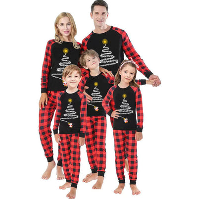 Family of five wearing matching black and red buffalo plaid Christmas pajamas with a white Christmas tree print. - Image 13
