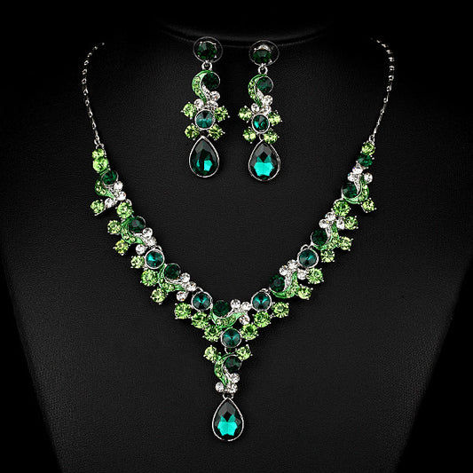 Pink and red rhinestone necklace and matching drop earrings set, featuring teardrop gems and floral scroll design.