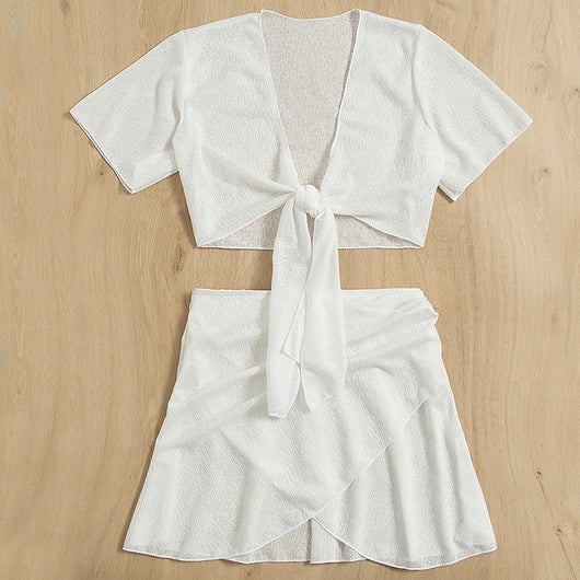 White two-piece swimwear set with a tie-front crop top and a high-waisted skirt with an asymmetrical ruffled hem. - Image 7