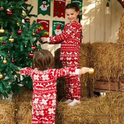 Family of four wearing matching red and white Christmas pajamas with reindeer and snowflake patterns, smiling. - Image 7