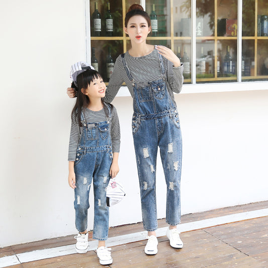 Mother and daughter wearing matching distressed denim overalls over black and white striped long-sleeve shirts. - Image 2