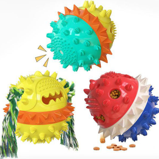Yellow spiky dog toy with orange band and green rope, designed for chewing and treat dispensing, next to a yawning puppy.