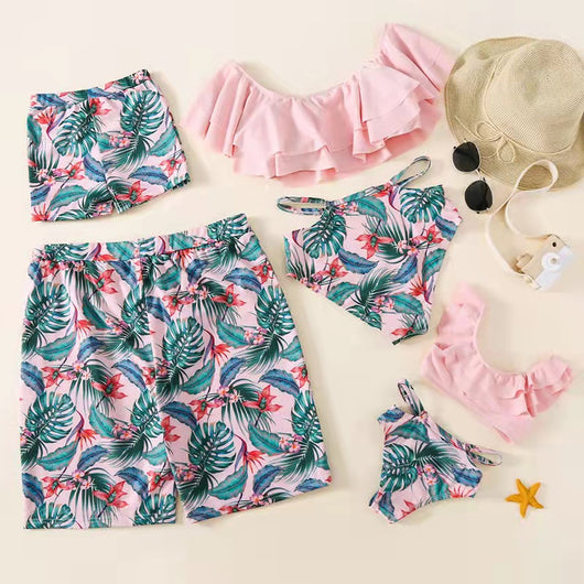 Family matching swimsuits with pink tropical floral and leaf print. Includes women's ruffled bikini, girl's one-piece, and men's/boy's swim shorts. - Image 10