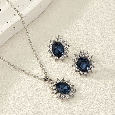 Iridescent teardrop pendant necklace with matching stud earrings, featuring clear accent stones and silver-tone metal.
