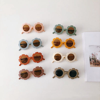 Orange flower-shaped sunglasses for babies and toddlers with dark lenses and a plastic frame.