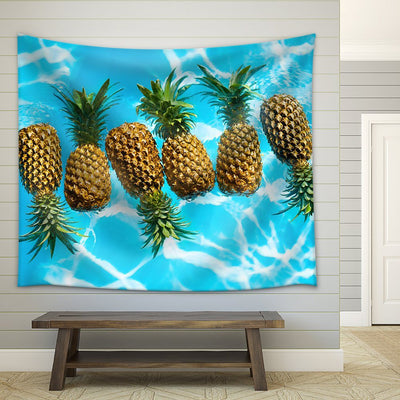 Printed tapestry featuring multiple pineapples floating in clear blue water with visible ripples and reflections.