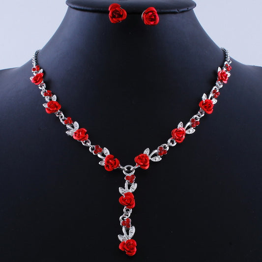 Red rose alloy necklace and stud earrings set with silver-tone chain and clear accents, displayed on a black bust.