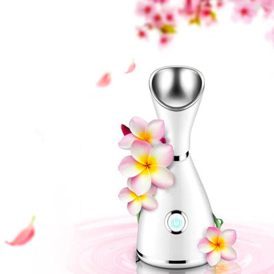 White facial steamer with a silver-toned steam nozzle and a prominent power button on the front, designed for home skincare.
