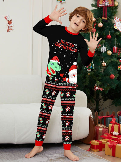 Man wearing black Christmas pajamas with a cartoon dinosaur, Santa Claus, and "Merry Christmas" text, standing by a decorated tree. - Image 22