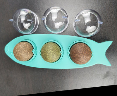 Pink fish-shaped cat molar stick toy with three compartments holding green and brown catnip or silvervine balls. Three clear plastic dome covers are shown. - Image 7