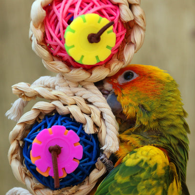 Colorful bird toy with three woven vine balls, internal pink, blue, and green string, felt flowers, and a bell. - Image 6