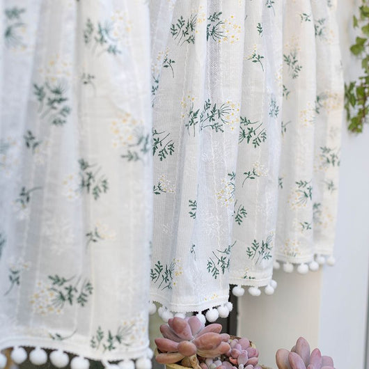 White semi-sheer curtain with green and grey floral pattern and cream tassel trim, hanging in a window. - Image 9