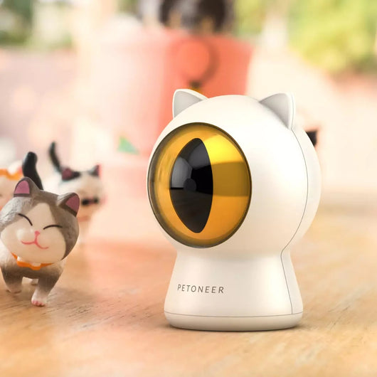 White cat-shaped laser toy with gold eye and red light, alongside a light blue smart rolling ball cat toy.