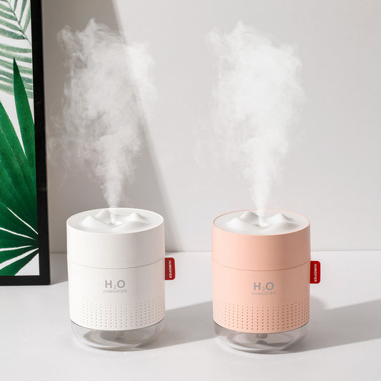 White cylindrical USB charging desktop humidifier with a clear base and a textured snow mountain top. Features 'H₂O HUMIDIFIER' text and a red tag.