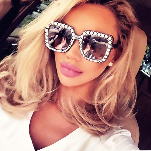 Oversized square sunglasses with clear peach frames, brown lenses, and clear faceted rhinestones around the edges.