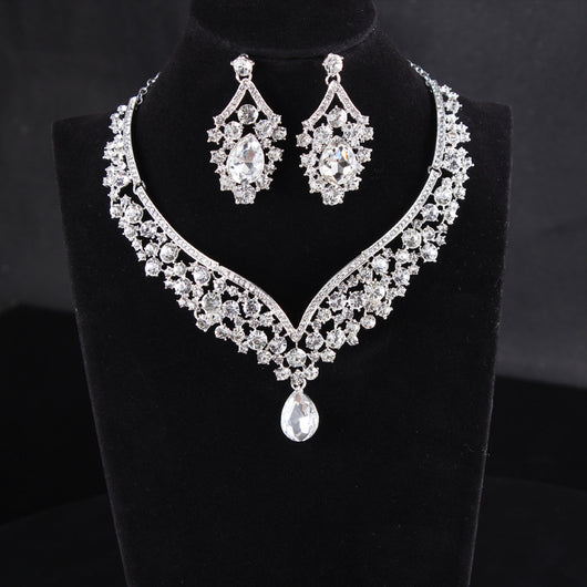 Sparkling silver-tone necklace and matching earrings set with clear round and teardrop rhinestones on a black display. - Image 3