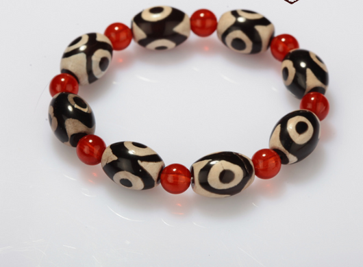 Three-eyed Dzi bead bracelet with alternating black and cream oval Dzi beads and round red agate beads. - Image 4