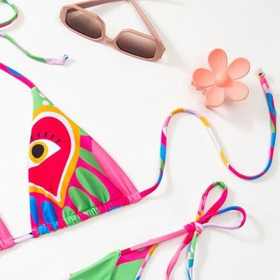 Women's vibrant abstract eye print bikini with triangle top and tie-side bottoms, featuring pink, green, and blue. - Image 2