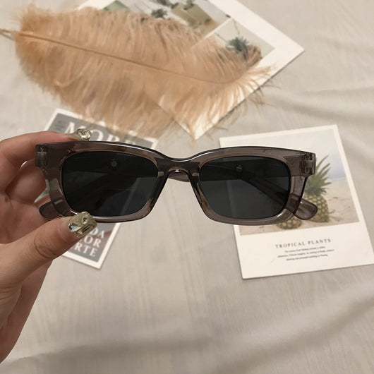 Square retro tortoise shell sunglasses with dark lenses, held by a hand against a blurred magazine background. - Image 3