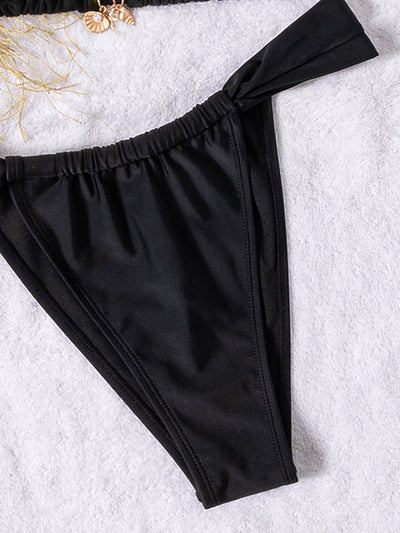 Black solid-color triangle-bra swimsuit with tie-front bikini bottom on a white towel with beach accessories. - Image 17