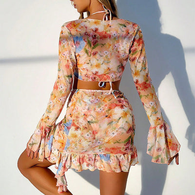 Four-piece women's beachwear set with a peach, blue, and green floral print. Includes a triangle bikini, long-sleeve tie-front cover-up, and ruched mini skirt. - Image 21