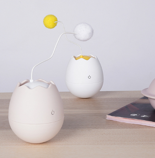 White egg-shaped automatic cat toy with a yellow interior and a flexible wire holding a yellow fuzzy ball. - Image 15
