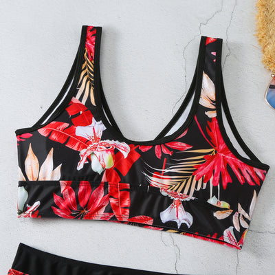 Two-piece swimsuit with a black background and vibrant pink and purple tropical floral print. Features a V-neck crop top and high-waisted boxer shorts. - Image 30