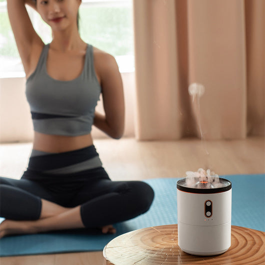 White volcanic flame aroma essential oil diffuser emitting orange light and mist on a wooden desk next to a laptop. - Image 12