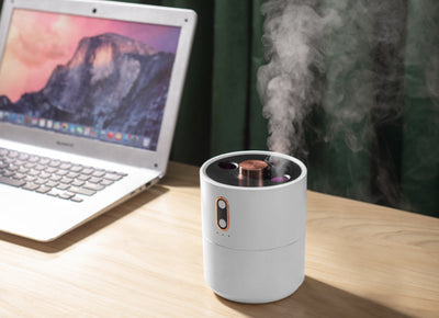 White volcanic flame aroma essential oil diffuser emitting orange light and mist on a wooden desk next to a laptop. - Image 17