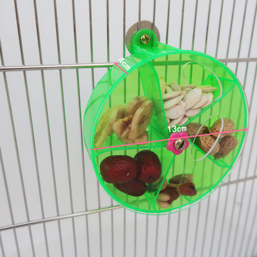 Clear acrylic bird foraging wind wheel toy with multiple compartments filled with nuts and dried fruit, attached to a bird cage. - Image 16