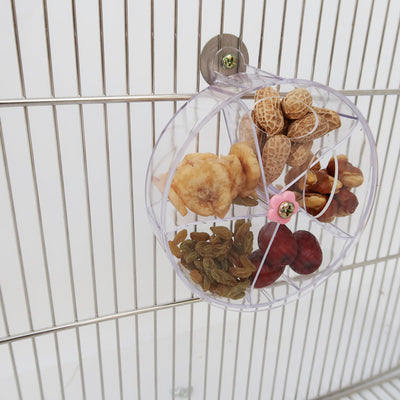 Clear acrylic bird foraging wind wheel toy with multiple compartments filled with nuts and dried fruit, attached to a bird cage. - Image 18