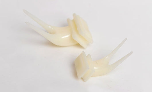 White plastic bird fruit fork clipped onto blue birdcage bars, designed to hold fruit or vegetables for pet birds. - Image 20