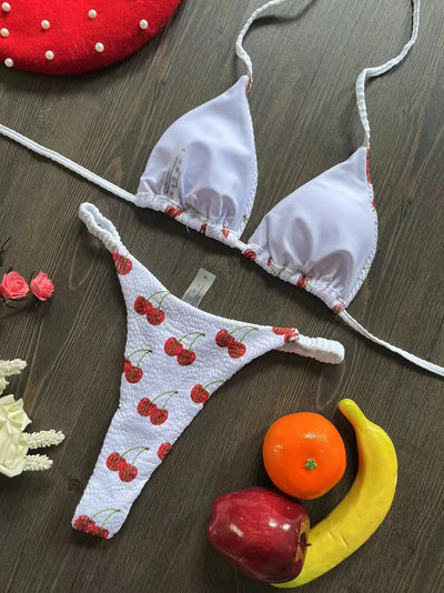 White textured bikini with red cherry print, featuring a triangle top and tie-side bottoms, on a woven mat. - Image 17
