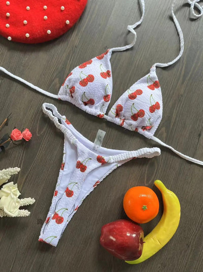 White textured bikini with red cherry print, featuring a triangle top and tie-side bottoms, on a woven mat. - Image 18