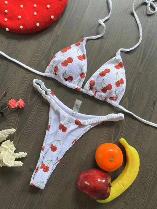 White textured bikini with red cherry print, featuring a triangle top and tie-side bottoms, on a woven mat. - Image 18